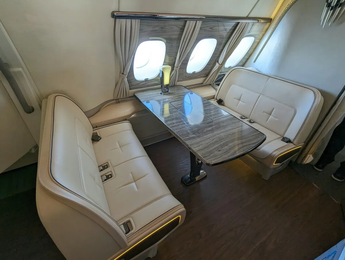 Cream leather club seats facing a polished table inside a business jet