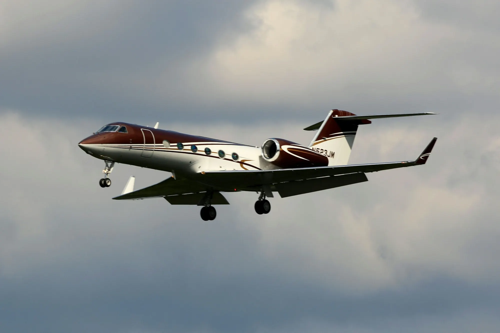 A midsize business jet in flight against soft grey cloud